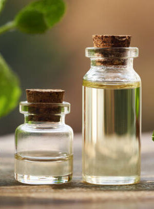 A glass bottle of aromatherapy essential oil with fresh peppermint plant